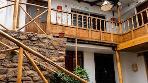 Un edificio tradicional con balcón de madera, paredes de piedra y una puerta negra.
