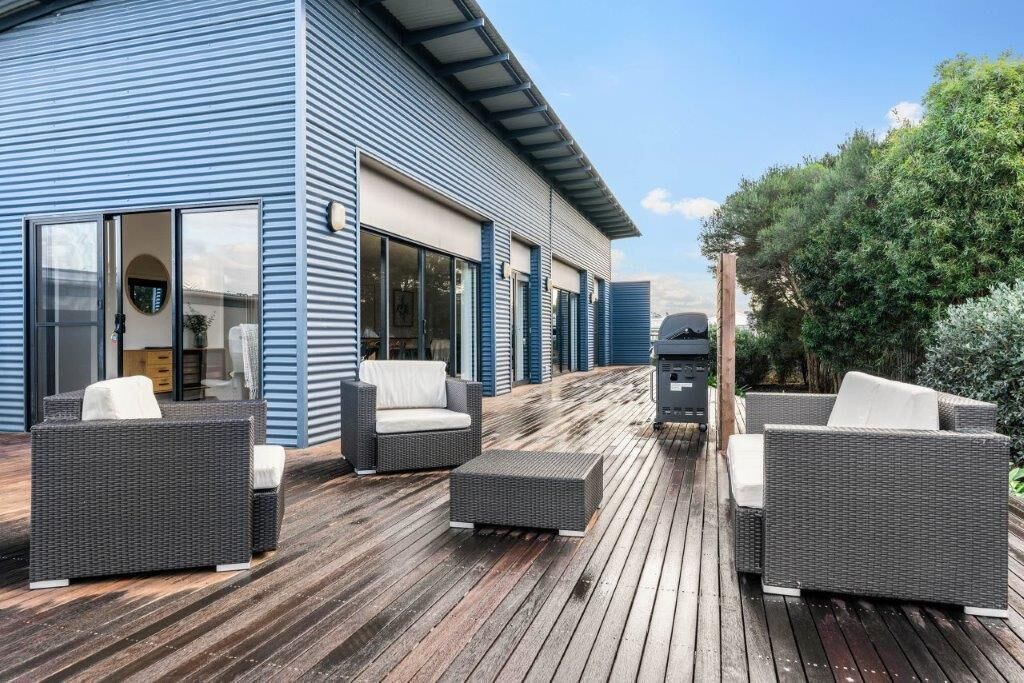 A modern outdoor deck with wicker furniture and a barbecue grill.