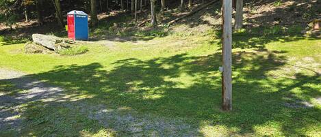 A forested area with a blue and red structure, possibly a restroom, and a wooden utility pole.