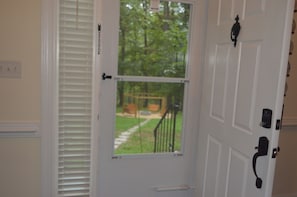 A white door with a window, a black doorbell, and a keypad lock.