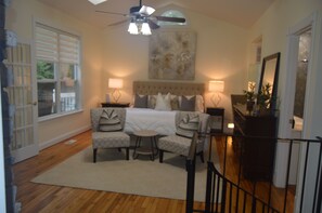 A bedroom with a bed, two chairs, a small table, a ceiling fan, and a large painting on the wall. - Mountain-Top HOUSE with a Pool, Near Potomac River Beach! in serene Stafford (Stafford)