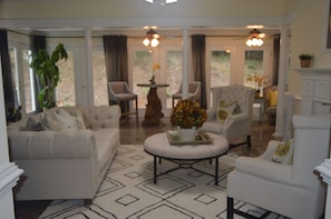 A spacious living room with a large sofa, two armchairs, a coffee table, and a fireplace.