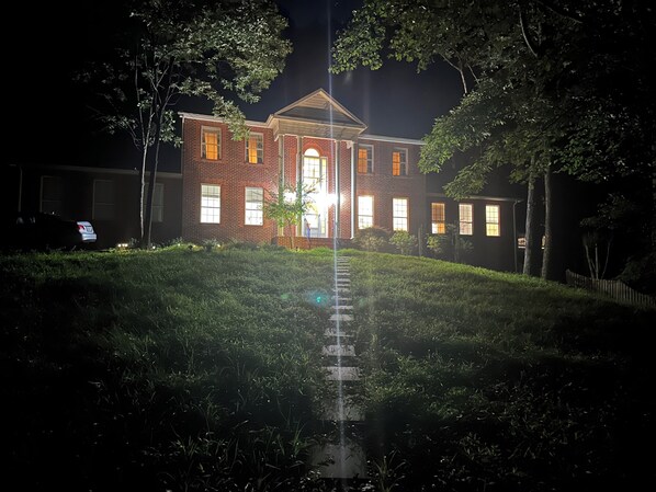 A brick building with a central entrance, surrounded by a well-maintained lawn and trees.