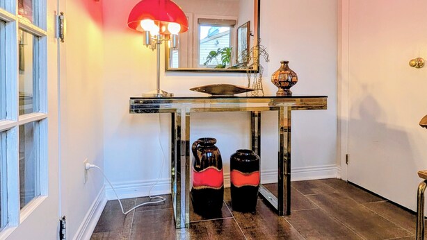A bathroom with a mirror, a sink, a red lamp, and two black vases. - Luxury Duplex in a Prime Location (Gatineau)