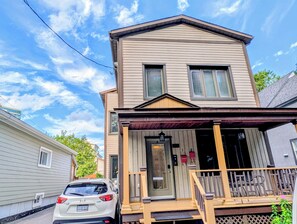 A two-story house with a front porch and a car parked in front. - Luxury Duplex in a Prime Location (Gatineau)