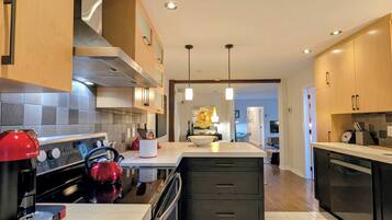 A modern kitchen with a central island, stainless steel appliances, and wooden cabinetry.