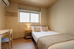 Ein Schlafzimmer mit einem Bett, einem Nachttisch, einer Lampe und einem Fenster.