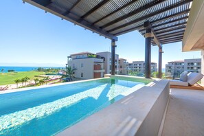 A poolside area with a view of the ocean and resort buildings. - Condo Sardan 3BD - Tau Punta Mita (Punta de Mita)