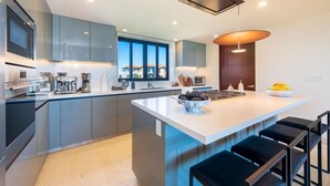 Une cuisine moderne dotée d’un îlot central, d’appareils électroménagers intégrés et d’une grande fenêtre.