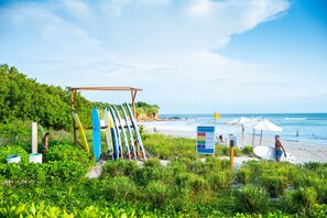 A beach with a surfboard rack, beach warning flags, and umbrellas. - Amor y Surf 5BD - Surf Punta Mita (Punta de Mita)