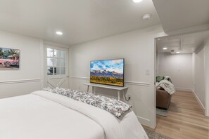 Une chambre à coucher avec un lit, un téléviseur fixé au mur et une porte donnant sur une salle de bain.
