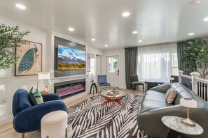 A modern living room with a fireplace, seating, and artwork. - Honey's Full House-Both Homes, Hot Tub, Sleeps 12 (Pocatello)