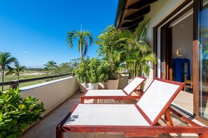 Ein Balkon mit zwei Holz-Loungestühlen, Topfpflanzen und Blick auf die Landschaft.