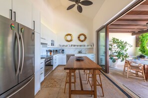 Eine moderne Küche mit Edelstahlgeräten, einem Holzespeisetisch und einem Deckenventilator.