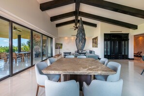 Ein modernes Interieur mit einem großen Esstisch, hellblauen Stühlen und einer hängenden Leuchte.