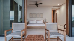 Una camera da letto con un letto, due sedie, un tavolo e una ventola a soffitto.