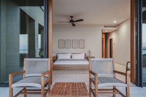A bedroom with a bed, two chairs, a table, and a ceiling fan. - Penthouse Arenamar 4BD - Surf Punta Mita (Punta de Mita)