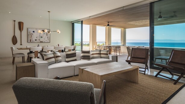 Un'ampia zona giorno con un'ampia finestra vista oceano, una ventola a soffitto e un design d'interni moderno.