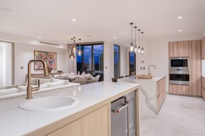 A modern kitchen with a large island, built-in appliances, and pendant lighting. - Condo Joya 3BD - Marietas Punta Mita (Punta de Mita)