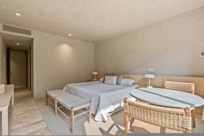 A bedroom with a bed, bedside tables, a bench, a round table, and wicker chairs. - Condo Perla de Mar 4BD - Uavi (Punta de Mita)