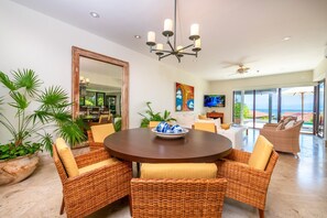 A dining area with a round table, wicker chairs, and a bowl of decorative items. - Villa Perla 3BD - Porta Fortuna Punta Mita (Punta de Mita)