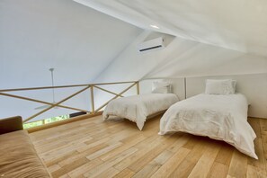 A bedroom with two beds, wooden flooring, a sloped ceiling, and a view of greenery outside. - Condo Pac Fico 3BD - Terrazas Punta Mita (Punta de Mita)