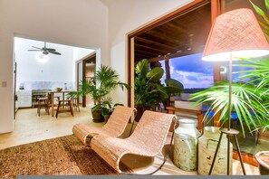A modern living room with a sofa, chairs, a dining area, and a view of the sky. - Condo Pac Fico 3BD - Terrazas Punta Mita (Punta de Mita)