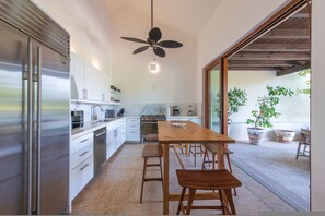 A modern kitchen with a central island, stainless steel appliances, and a ceiling fan. - Condo Pac Fico 3BD - Terrazas Punta Mita (Punta de Mita)