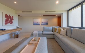 Ein modernes Wohnzimmer mit Ecksofa, Couchtisch aus Holz und Kunstwerken an den Wänden.