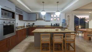 Una cocina moderna con encimeras de granito, electrodomésticos de acero inoxidable y una isla central con taburetes de bar.