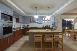 Eine moderne Küche mit Granit Arbeitsplatten, Edelstahlgeräten und einer zentralen Kochinsel mit Barhocker.