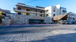 Un hotel con fachada de piedra, varios balcones y una estructura de tejado de paja.