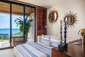 Ein Schlafzimmer mit einem großen Bett, Meerblick und einem Balkon mit Pflanzen.