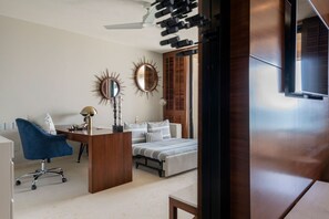 Un dormitorio moderno con un escritorio, una silla azul, una cama con ropa de cama a rayas y dos espejos fijados a la pared.