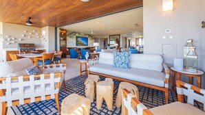 A spacious living area with a wooden ceiling, a white sofa with blue patterned pillows, and a dining area with wooden furniture. - Casa Escrita 3BD - Tau Punta Mita (Punta de Mita)