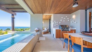 A modern outdoor kitchen with a pool and a dining area, overlooking a scenic view. - Casa Escrita 3BD - Tau Punta Mita (Punta de Mita)