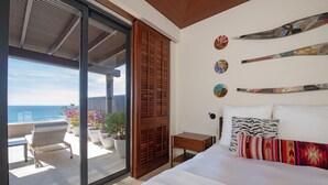 A bedroom with a large bed, a wooden door, a small bedside table, and a view of the ocean through a sliding glass door. - Ph Bugambilia 4BD - Tau Punta Mita (Punta de Mita)