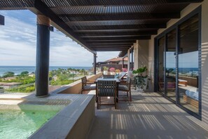 Ein Balkon mit Blick auf den Ozean, ein Schwimmbad und ein Tisch mit Stühlen.