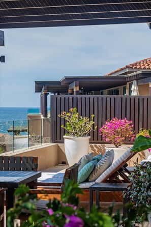 Eine Terrasse mit Meerblick, ausgestattet mit einer Lounge mit Kissen und einem Tisch.