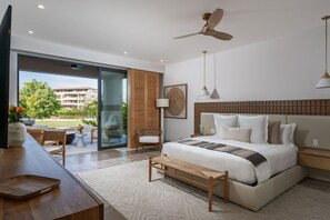 A modern bedroom with a large bed, a ceiling fan, and a view of a building through a glass door. - Villa Buena Vida 4BD - Porta Fortuna Punta Mita (Punta de Mita)