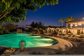 A swimming pool with lounge chairs and umbrellas, surrounded by palm trees and a night sky. - Villa Amada 5BD - Porta Fortuna Punta Mita (Punta de Mita)