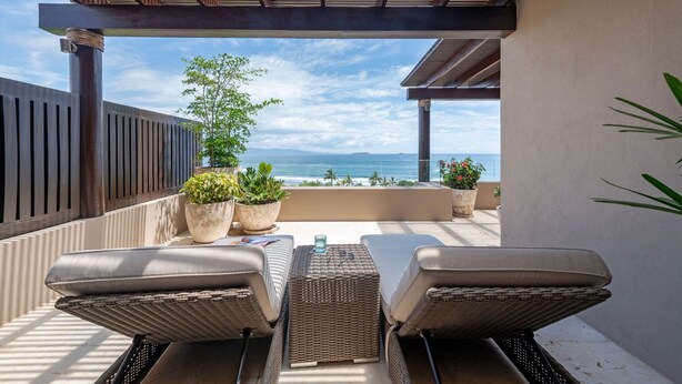 A covered outdoor seating area with two wicker chairs, a small table, and potted plants. - Vista Ballena 4BD - Tau Punta Mita (Punta de Mita)
