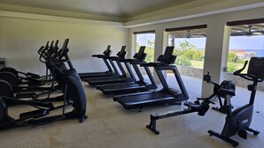 A gym with treadmills, elliptical machines, and a stationary bike, with large windows offering a view of the outdoors. - Vista Ballena 4BD - Tau Punta Mita (Punta de Mita)