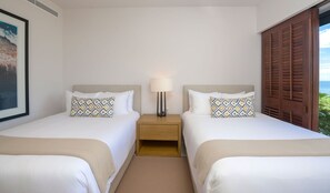 Ein Hotelzimmer mit zwei Betten, einem Nachttisch mit Lampe und Blick aufs Meer.