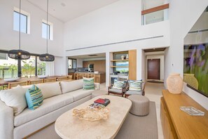 Ein modernes Wohnzimmer mit Sofa, Couchtisch und Essbereich, im Hintergrund eine Küche.