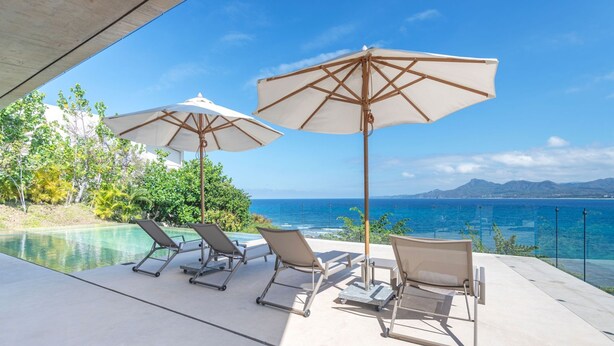 A poolside area with lounge chairs and umbrellas, overlooking a clear blue sea and distant mountains. - Casa Morgandez 5BD - Iyari Punta Mita (Punta de Mita)