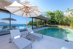 A modern outdoor pool area with lounge chairs and a large umbrella. - Casa Morgandez 5BD - Iyari Punta Mita (Punta de Mita)