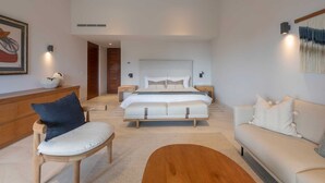 Un dormitorio moderno con una cama grande, un banco de madera, un sofá y una mesa de centro.