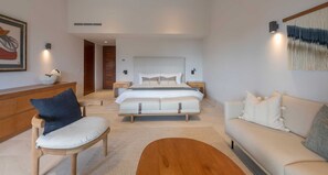 A modern bedroom with a large bed, a wooden bench, a sofa, and a coffee table. - Villa Amistad 4BD - Porta Fortuna Punta Mita (Punta de Mita)