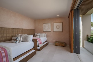 Ein Schlafzimmer mit zwei Betten, einem Holzkopfteil, einer Kommode und zwei gerahmten Kunstwerken an der Wand.